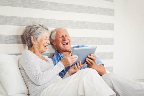 Senior couple on couch laughing at tablet